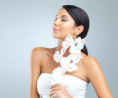 Buy stock photo Flowers, skincare and woman with beauty, glow and person on a grey studio background. Model, luxury or girl with aesthetic or natural with facial or shine with dermatology and smooth skin with health
