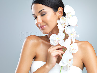 Buy stock photo Flowers, cosmetics and woman with beauty, shine and person on grey studio background. Model, luxury or girl with aesthetic or natural with facial, plants or shine with glow and skincare with wellness