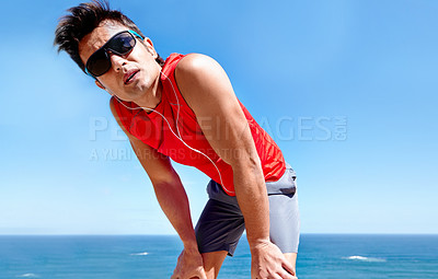 Buy stock photo Runner, man and tired with earphones at beach with rest, break or breathing with music in summer sunshine. Person, listening and streaming with subscription with workout, memory and fitness by ocean