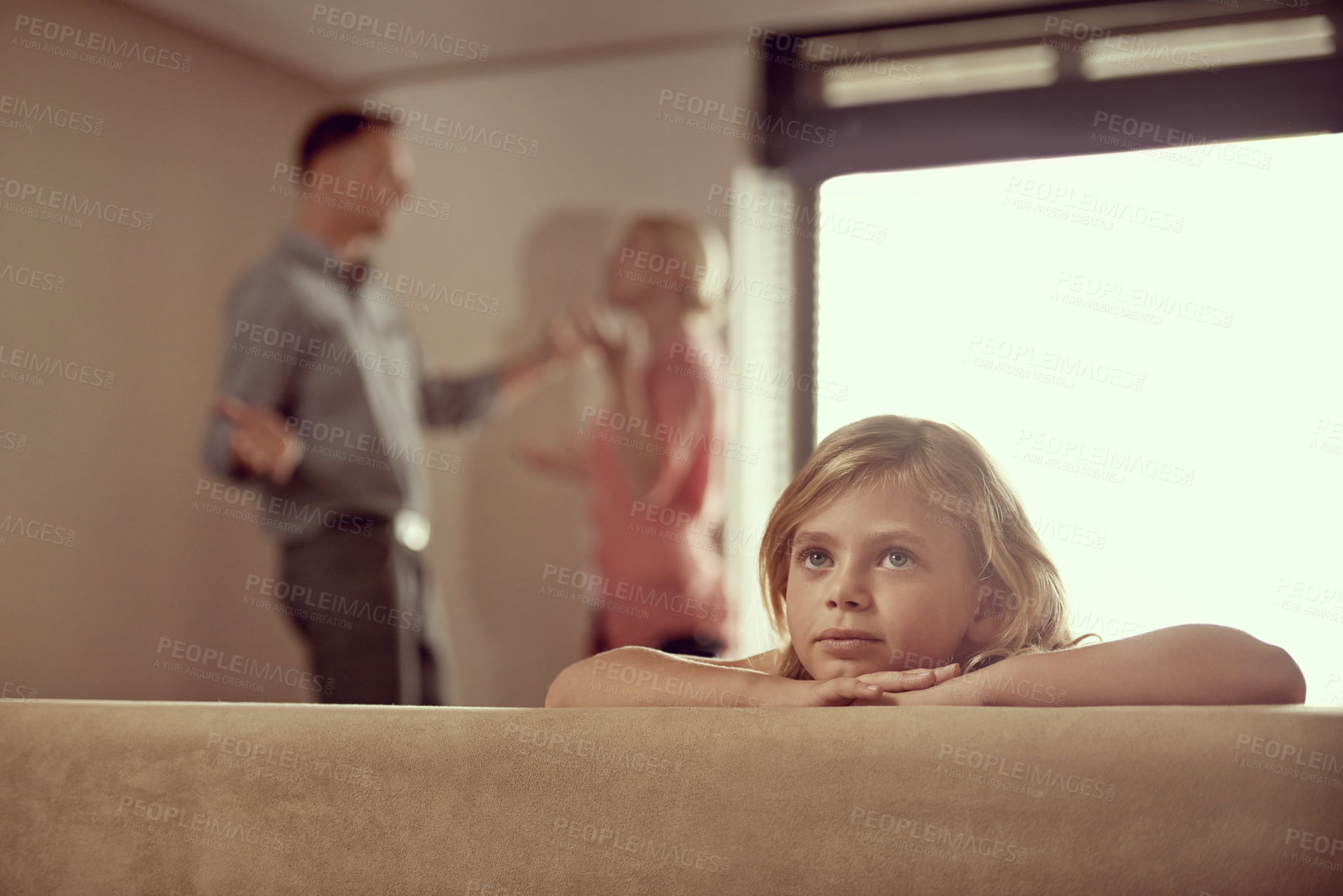 Buy stock photo Shot of a little girl looking unhappy as her parents argue in the background