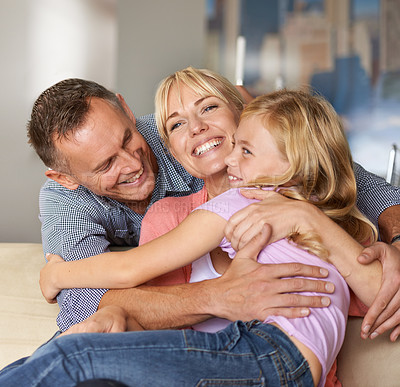 Buy stock photo Happy, child and parents on sofa with love, relax and bonding together in home on weekend. Father, mother and daughter with care in family, playing and excited on vacation with hugging in apartment