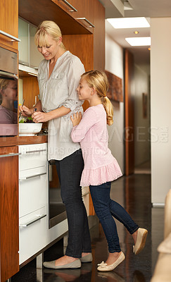 Buy stock photo Shot of a cute girl and her mother cooking in the kitchen