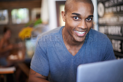 Buy stock photo Cropped shot of a handsome young man using his laptop in a coffee shop