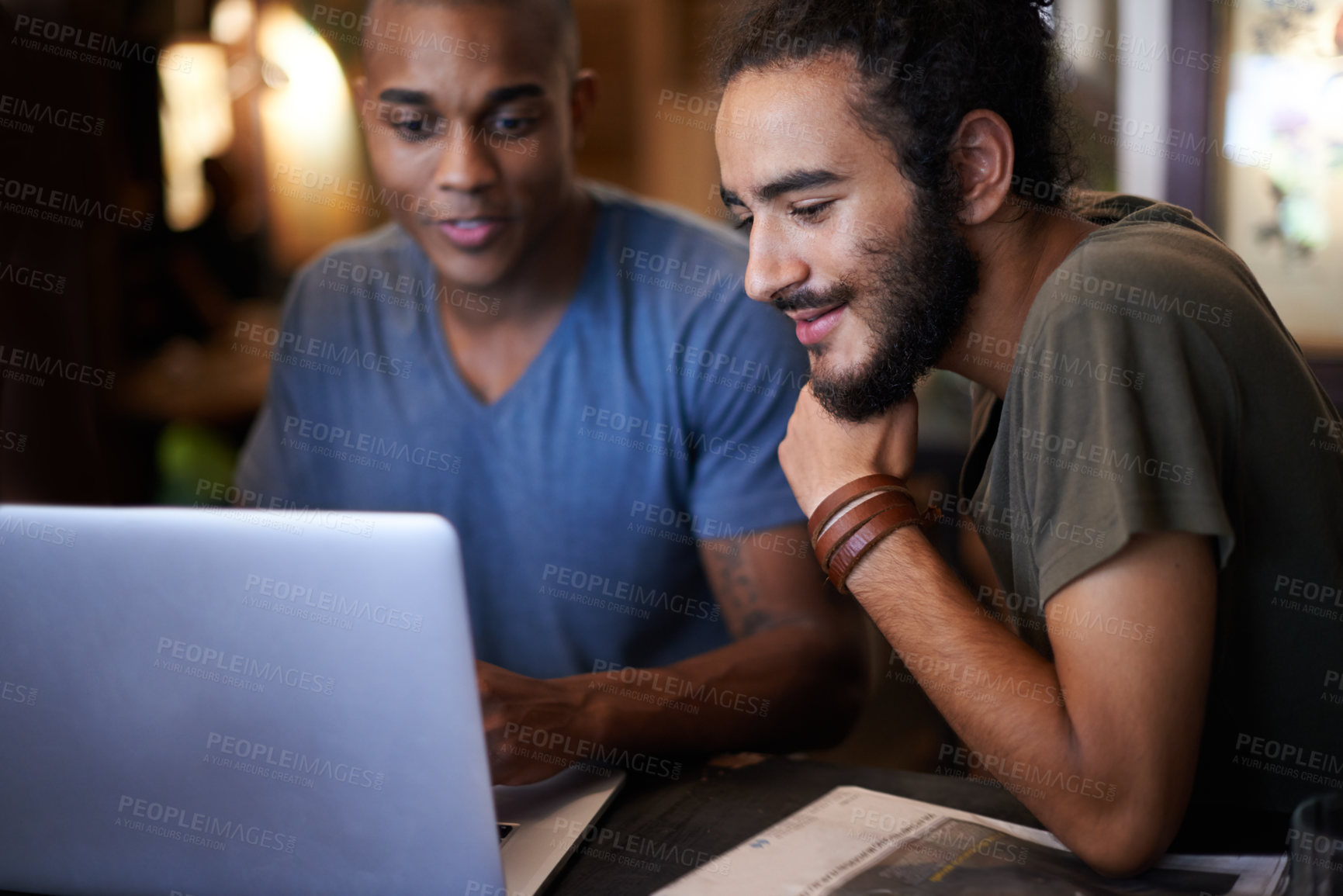 Buy stock photo Cropped shot of two male friends using a laptop in a coffee shop