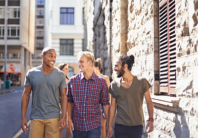Buy stock photo Male friends, walking and talking in city, smile and conversation on travel holiday. Urban, fun and diverse group of happy men, discussing and bonding while out on stroll in New York on vacation