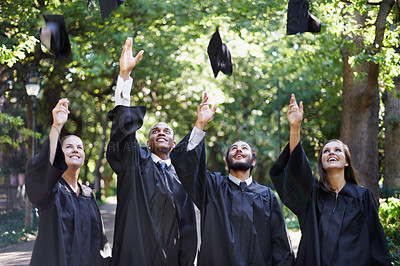 Buy stock photo A group of happy university students throwing their caps into the air on graduation day