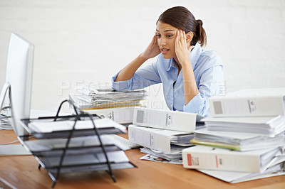 Buy stock photo A young businesswoman looking overwhelmed while surrounded by paperwork