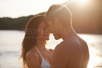 Buy stock photo Love, sunset and couple on island for date on romantic anniversary vacation, adventure or holiday. Smile, bonding and young man and woman embracing with care by ocean on weekend trip together.