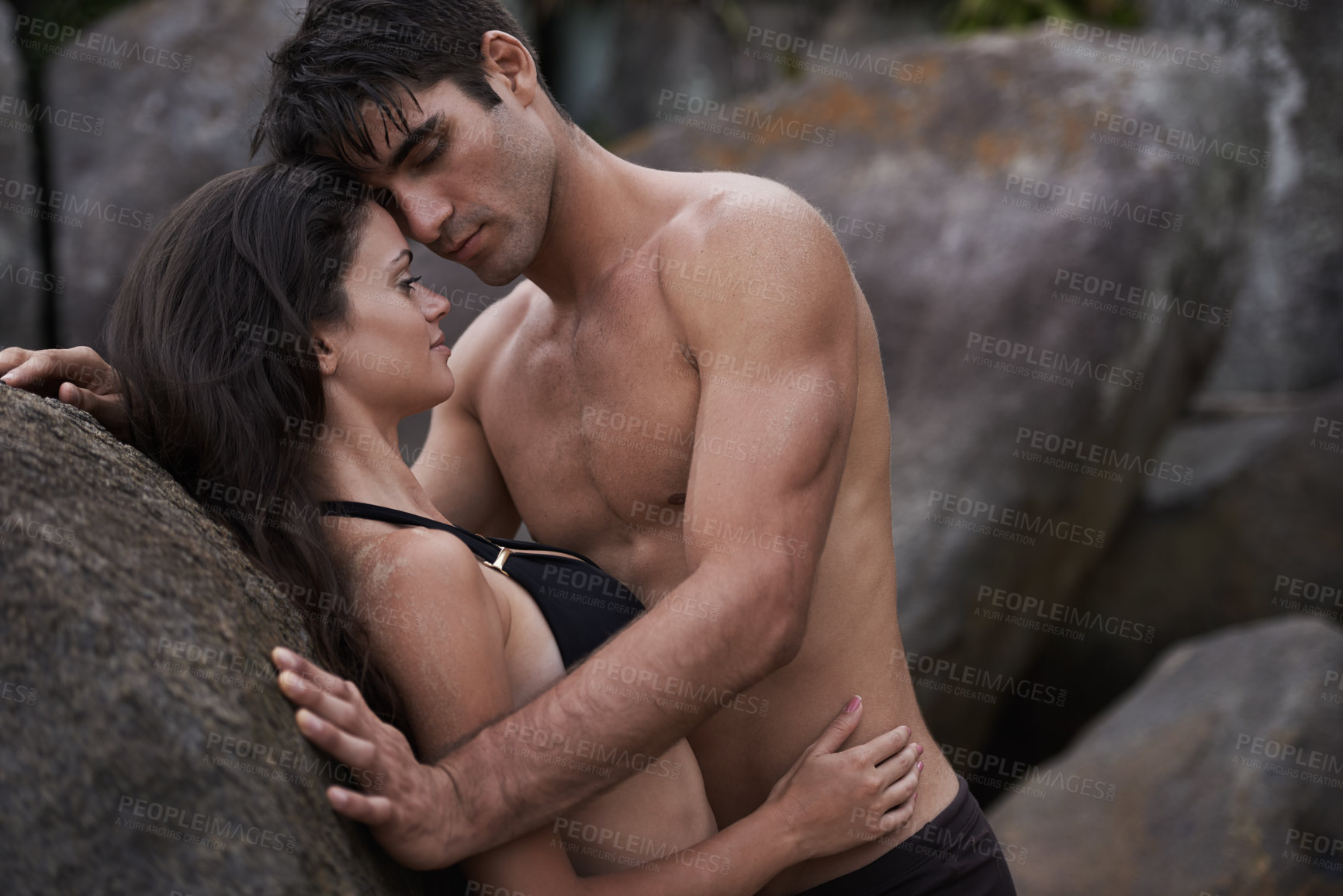 Buy stock photo Couple, beach and rocks with love, relationship and romance with swimwear and bikini. Man, woman and date with holiday, vacation and adventure with nature for cape town summer travel and sensuality
