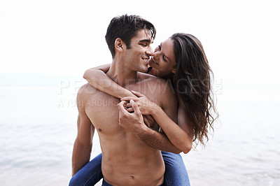 Buy stock photo A cropped shot of a young man giving his girlfriend a piggyback ride on the beach