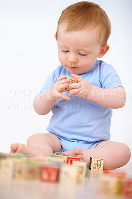 Buy stock photo Boy, baby and playing with wooden blocks or toys for childhood development on a gray studio background. Little toddler, cute or adorable child learning shapes, letters or building on mockup space