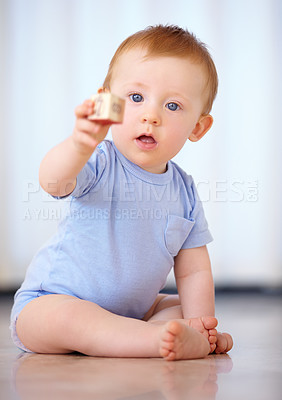 Buy stock photo Baby, portrait and playing with wooden blocks or toys for childhood development on a gray studio background. Little boy, cute toddler or child on floor with shape or cube for building or learning