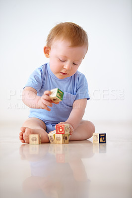 Buy stock photo Baby boy, wooden blocks and playing with toys in early childhood development on a gray studio background. Little toddler or child on floor with shape or cube in building, learning or cognitive skills