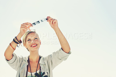 Buy stock photo A beautiful young woman in a studio holding up a strip of negatives