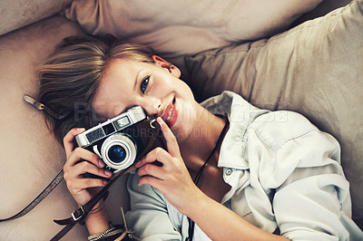 Buy stock photo High angle view of a beautiful young woman taking a photograph while lying on a couch