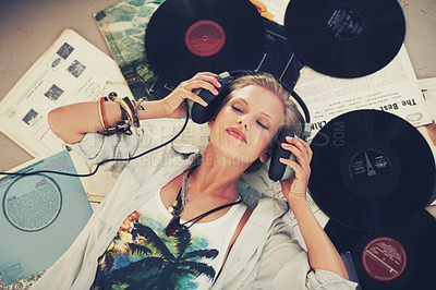 Buy stock photo A young woman listening to music while lying on her back and surrounded by records