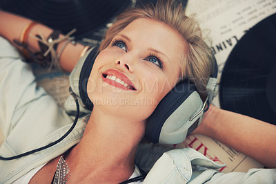 Buy stock photo Cropped shot of a beautiful young woman listening to music while lying indoors