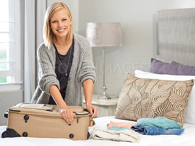 Buy stock photo Shot of a young woman packing her suitcase