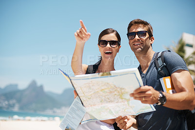 Buy stock photo Couple, map and search with pointing by sea, mountains or excited for giving direction on vacation. Woman, man and chart for location, landmark or travel for memory by rocks, ocean or nature in Italy