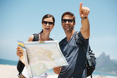 Buy stock photo Couple, map and search with pointing by beach, mountains and excited for giving direction on vacation. Woman, man and chart for location, landmark and travel for memory in holiday by ocean in Italy