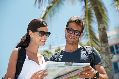 Buy stock photo Couple, map and search by palm tree on vacation, street and excited for giving direction. Woman, man and chart for location, landmark and travel for memory with buildings, nature or thinking in Italy