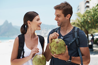 Buy stock photo Young couple enjoying a drink from a coconut while enjoying a day at the beach