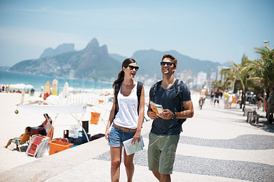 Buy stock photo Couple, tourist and walk in beach with map on holiday in summer, trip and happy in Brazil. Relationship, vacation and bonding in seaside for summer with adventure, travel and smile for break. 