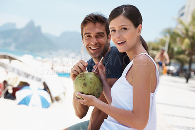 Buy stock photo Couple, coconut and drink at beach with smile for vacation with milk, cocktail and juice in portrait. People, man and woman with sunshine, review and fruit for water, happy and detox with nutrition