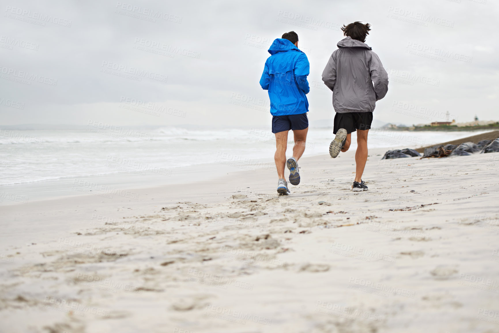 Buy stock photo Rear view, men and running on beach, sand and fitness for wellness and gym wear in cold coast. Male athletes, jog and training for seaside, health and outdoor for sport and exercise together