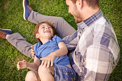 Buy stock photo Family, man and child on grass in garden, park or outdoors for talking, bonding and playing together. Young boy and smiling with dad on lap for innocent jokes and fun while laughing for happiness  