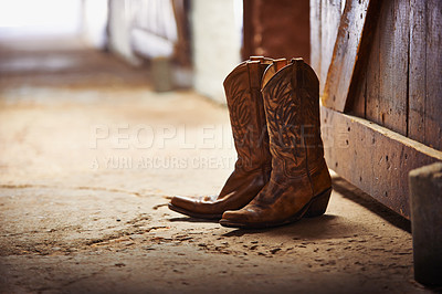 Buy stock photo Shot of a pair of cowboy boots in a barn