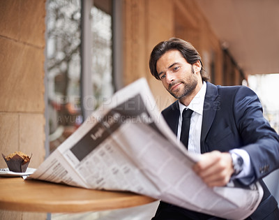 Buy stock photo A young businessman reading a newspaper outdoors at a coffee shop