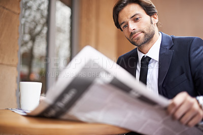 Buy stock photo A young businessman reading a newspaper outdoors at a coffee shop