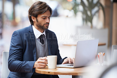 Buy stock photo A handsome businessman working on his laptop at a coffeeshop
