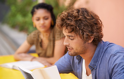 Buy stock photo Face, education and student man reading on college or university campus for learning and study. Book, scholarship and pupil with young person outdoor for research on break or recess at school
