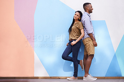 Buy stock photo Shot of a young couple standing back-to-back against a colorful wall