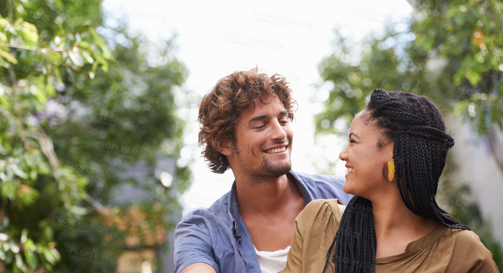 Buy stock photo Interracial, couple and smile together in nature, happy and love in diversity people with tree in backyard. Happiness, affection or staring, outdoor for relationship growth or commitment for romance