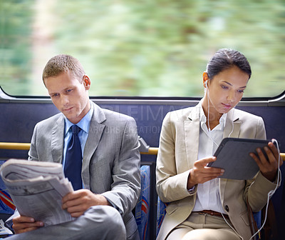 Buy stock photo Two business people reading catching up on the news on their commute to work