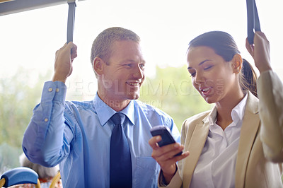 Buy stock photo Two young colleagues traveling on the bus and holding onto the hand straps