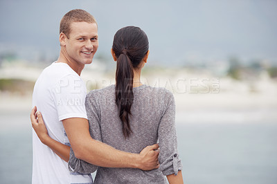Buy stock photo Shot of a young couple looking at the views on the beach