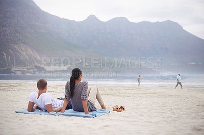 Buy stock photo Couple, beach and vacation on blanket, picnic or relaxing on seashore by mountains. Romantic, honeymoon and love between happy husband and wife, married and date on ocean coast enjoying sunshine