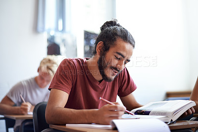 Buy stock photo College, student and man with smile for learning with  textbook, scholarship and studying for education. Male person, happy and reading for information with research on table or desk of classroom