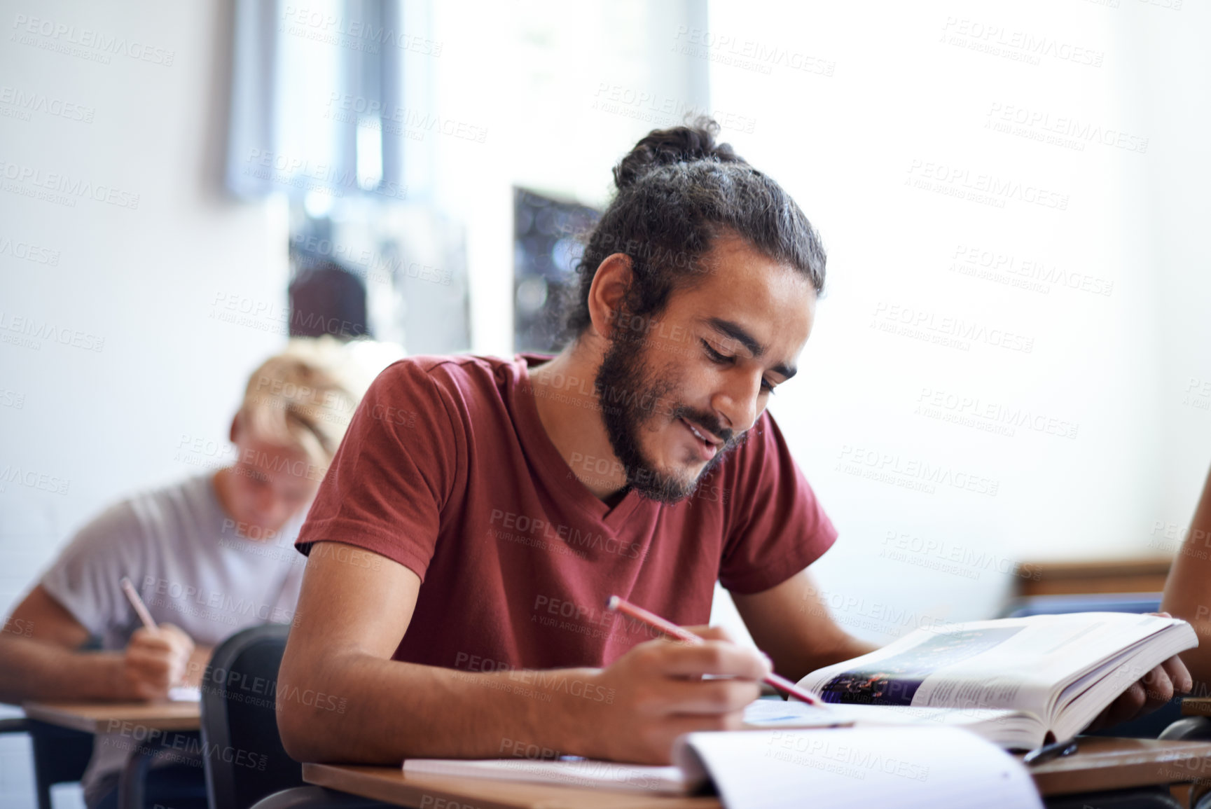 Buy stock photo College, student and man with smile for learning with  textbook, scholarship and studying for education. Male person, happy and reading for information with research on table or desk of classroom