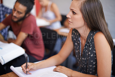 Buy stock photo Woman, student and writing with book in classroom for notes, summary or studying at university. Female person or academic writer taking notes for assignment, test or literature exam on desk at campus
