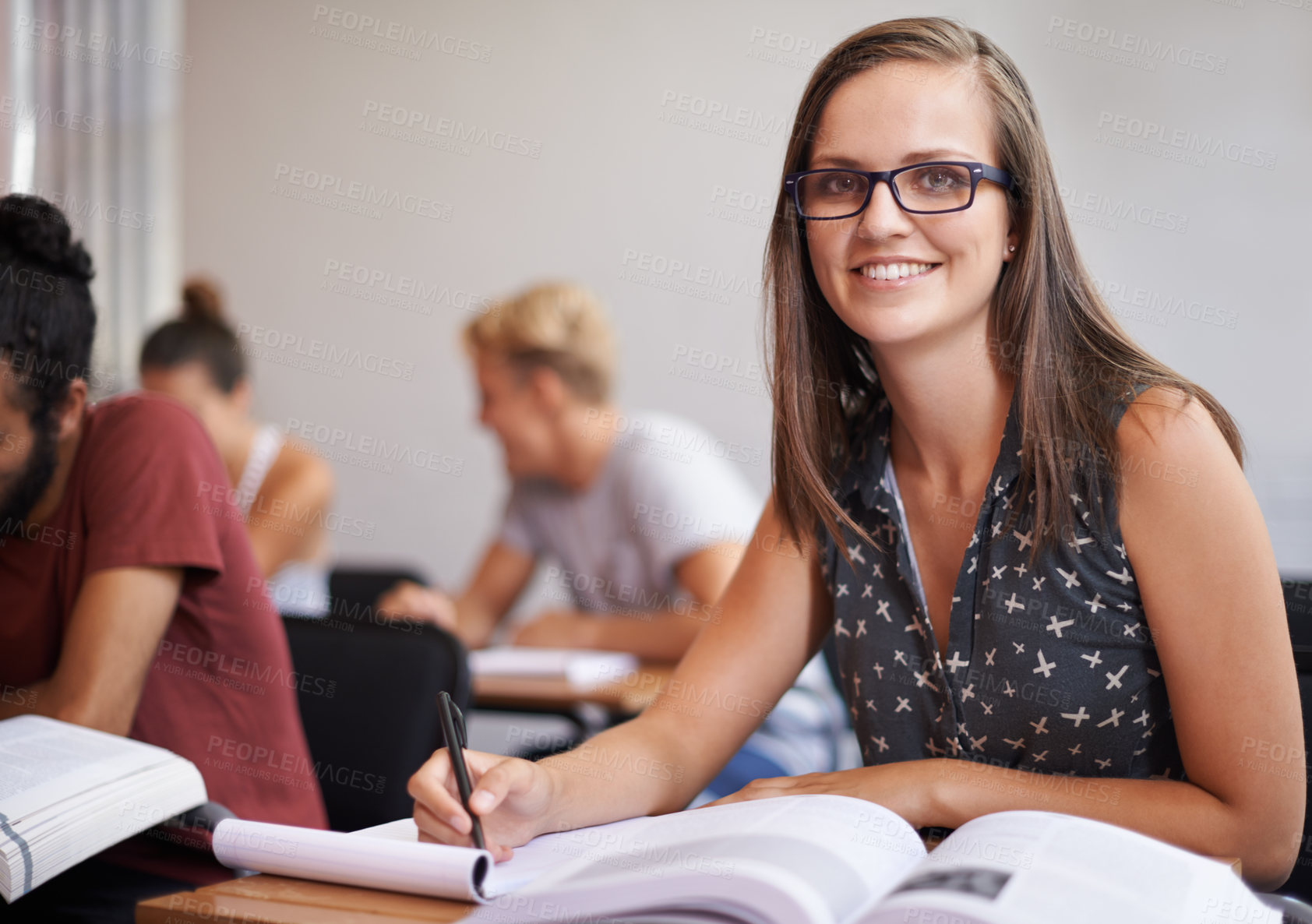 Buy stock photo An attractive young varsity student sitting in a classroom with a textbook in front of her