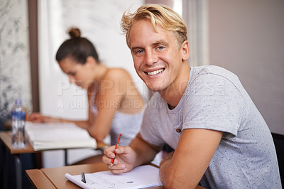 Buy stock photo Happy man, portrait and student with book in classroom for studying, reading or writing summary at university. Male person or academic writer with smile for assignment, test or exam on desk at campus