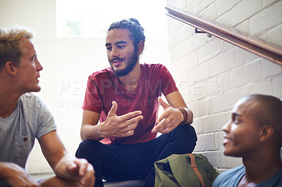 Buy stock photo Shot of male university students sitting and talking before class