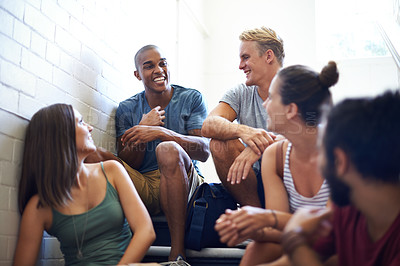Buy stock photo Cropped shot of university students talking while sitting on the steps of a stairwell