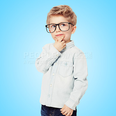 Buy stock photo Child, boy and thinking on frame choice or eyecare in studio, lenses and glasses for sight. Male person, kid and optometry or contemplating decision for style, fashion spectacles and blue background