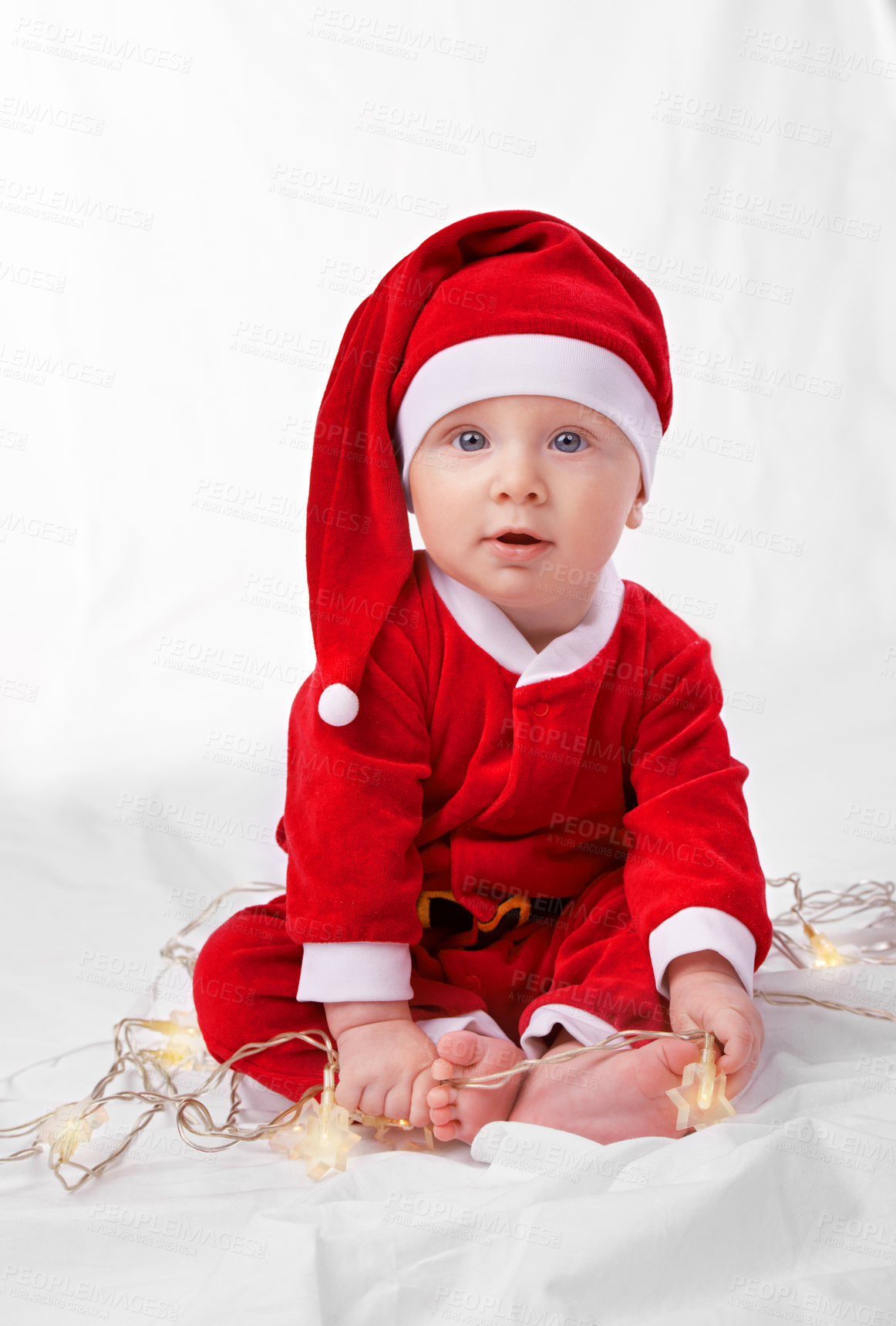 Buy stock photo Baby, portrait and cute with santa costume for first Christmas holiday, star lights and white background. Boy toddler, xmas and outfit for festive season or celebration, innocent and adorable in hat.